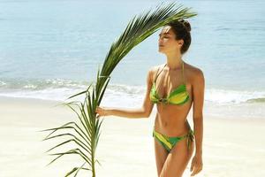 bellissimo donna con un' palma foglia su il spiaggia foto