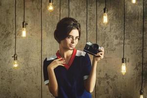 donna nel Vintage ▾ Guarda Tenere retrò telecamera nel sua mani foto
