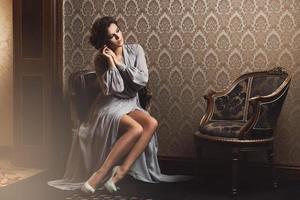 sbalorditivo donna nel un' bellissimo vestito seduta su il poltrona foto