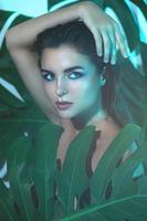 giovane e bellissimo donna con Perfetto liscio pelle nel tropicale le foglie foto