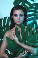 giovane e bellissimo donna con Perfetto liscio pelle nel tropicale le foglie foto