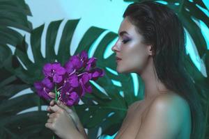 giovane e bellissimo donna con Perfetto liscio pelle è Tenere orchidea fiori foto