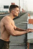 muscolare uomo con nudo torso durante fitness allenarsi su un' ponte foto