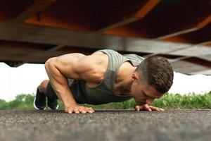 muscolare uomo è fare sollevamento durante calisthenic allenarsi su un' strada foto