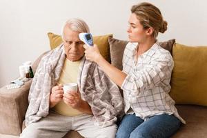 donna assunzione cura di sua anziano nonno con un' freddo sintomi foto