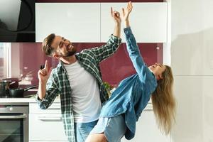 coppia danza su il cucina mentre cucinando durante soleggiato mattina foto