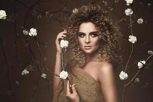 bello giovane donna con afro acconciatura e bellissimo trucco con un' lotto di bianca fiori foto