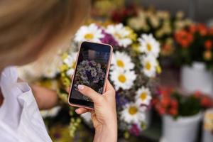 donna fioraio è assunzione foto di fiori selvatici mazzo per un' cliente nel sua poco fiore negozio