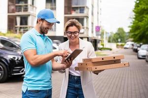 consegna uomo indossare blu uniforme consegna Pizza per un' donna cliente foto