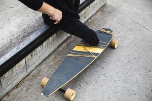 portatori di handicap giovane tipo con un' longboard nel parco foto