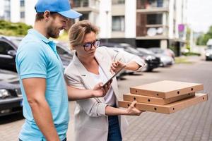 consegna uomo indossare blu uniforme consegna Pizza per un' donna cliente foto