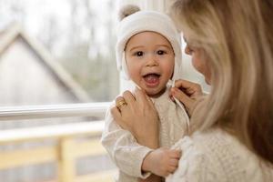 madre mettere un' a maglia cappello su sua bambino ragazzo foto