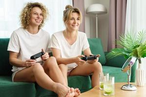 Due bellissimo ragazze giocando video gioco consolle nel vivente camera foto