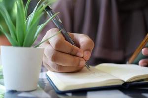 vicino su di donne mano scrittura su bloc notes. foto