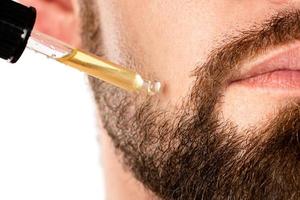 maschio viso e pipetta con un' olio per un' barba crescita foto