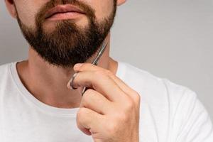 uomo Rifinitura il suo barba con un' forbici foto