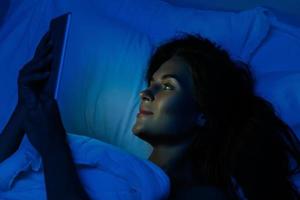 giovane donna è utilizzando tavoletta pc a notte tempo nel il letto foto