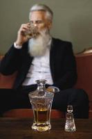 bello e barbuto anziano uomo potabile whisky foto