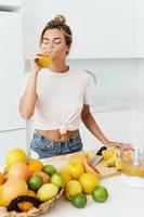 donna potabile appena spremuto fatti in casa arancia succo nel bianca cucina foto