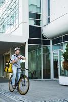 esprimere consegna Corriere con isolato Borsa guardare a orologio su bicicletta. foto