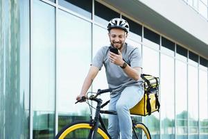 esprimere consegna Corriere con isolato Borsa guardare a Telefono su bicicletta. foto