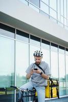 esprimere consegna Corriere con isolato Borsa guardare a Telefono su bicicletta. foto