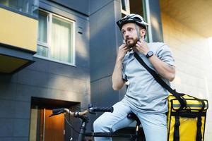 esprimere consegna Corriere su bicicletta mette su casco. foto