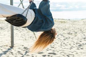 giovane donna oscillante su il swing a il sabbioso spiaggia. foto