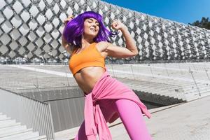 spensierato attivo donna ballerino indossare colorato abbigliamento sportivo avendo divertimento su il strada foto