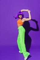 spensierato donna ballerino indossare colorato abbigliamento sportivo l'esecuzione contro viola sfondo foto