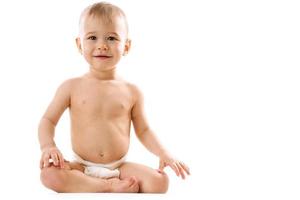 curioso salutare poco ragazzo nel pannolino seduta e sorridente. foto