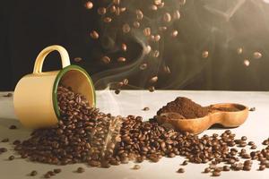 tazza di caffè e fagioli sparsi e caffè macinato in una ciotola di legno su sfondo bianco foto