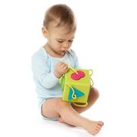 poco ragazzo nel pagliaccetto seduta e giocando con plastica giocattolo. foto