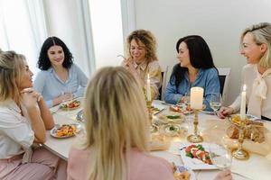 giovane donne amici ridendo a il festivo tavolo. foto