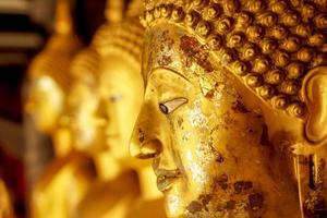 avvicinamento e Ritaglia vecchio e d'oro viso di d'oro Budda statua su sfocato d'oro Budda statua In piedi forte linea sfondo foto