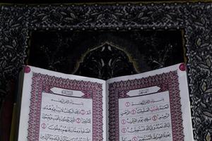 al-quran quale è sopra il preghiera tappeto con un' nero sfondo foto