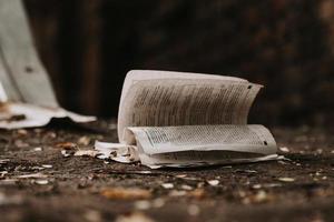 Aperto libro e spiegazzato pagine su il sporco terra. foto