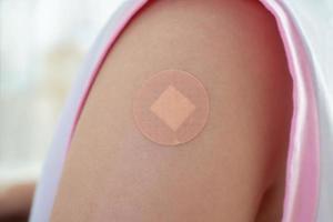 vaccinati poco asiatico ragazza con adesivo gesso dopo vaccino iniezione foto