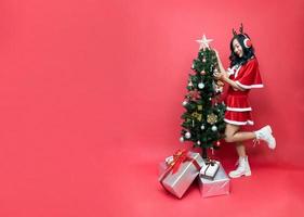 giovane Asia donna nel rosso santy costume decorare il Natale albero. nuovo anno celebrazione. Natale vigilia. foto