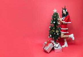 bellissimo Asia donna nel rosso santy costume decorare il Natale albero. nuovo anno celebrazione. Natale vigilia. foto