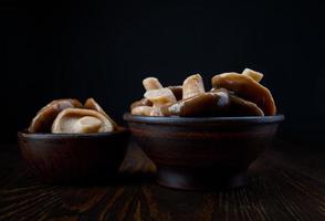delizioso sottaceto funghi nel argilla tazze In piedi su un' di legno tavolo . salato funghi . rustico cibo . foto