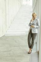 donna d'affari utilizzando mobile Telefono su moderno ufficio corridoio foto