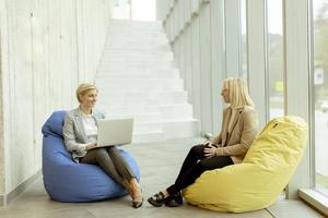 donne d'affari utilizzando il computer portatile computer su pigro borse nel il moderno ufficio foto