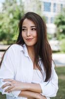 ritratto di giovane asiatico donna alunno con lungo capelli nel città parco foto