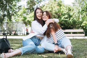 giovane bellissimo asiatico ragazze con lungo capelli nel casuale Abiti, amici avendo divertimento nel città parco foto