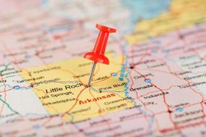 rosso clericale ago su un' carta geografica di Stati Uniti d'America, Arkansas e il capitale poco roccia. vicino su carta geografica di Arkansas con rosso bordeggiare foto