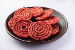 beatroot chakli, Murukku, barbabietola chakli, un' spirale fritte merenda a partire dal India fatto nel Diwali Festival foto