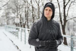 atletico uomo indossare felpa con cappuccio durante il suo inverno allenarsi nel nevoso città parco foto