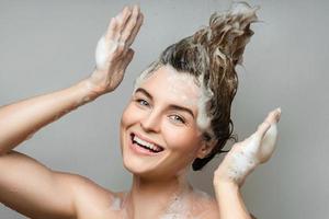 allegro bellissimo donna è lavaggio sua capelli con un' shampoo foto