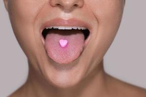 metà di femmina viso con cuore sagomato pillola su lingua. foto
